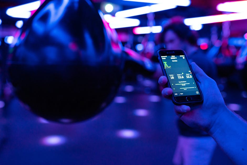 Smartphone displaying fitness tracking data next to boxing equipment under neon lighting.